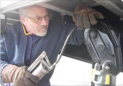 Manual grease guns, such as the one used on this landing gear, are recommended over air-powered guns to avoid forcing grease into the fitting too rapidly. Use a grease gun that holds a large volume of grease and has a long handle that gives you a large mechanical advantage.