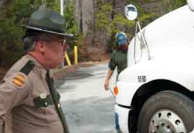 Tennessee Highway Patrol Trooper Robert Hadden looks on as an owner-operator opens his hood for inspection of the steering mechanism at the eastbound scale house on I-24 in Manchester, Tenn.