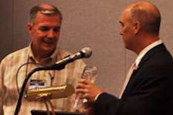 Trucker Buddy’s Randy Schwartzenburg (right) gives Randall-Reilly CEO Mike Reilly a plaque in appreciation of his support for Trucker Buddy.