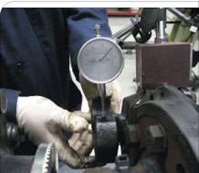 Install a dial indicator so the stem rests on top of the camshaft, with the dial at zero, prior to measuring clearance.