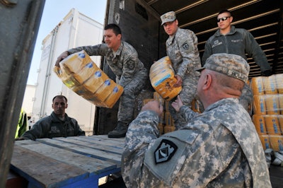 Members of West Virginia’s National Guard unload a trailer full of pet food in Charleston, W. Va., this week to distribute to members of the community in need of commodities.