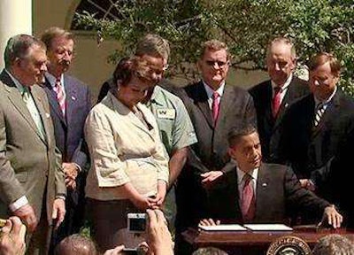 President Obama signs the original heavy truck fuel efficiency standards in 2011 at the White House, alongside Cabinet members and representatives from the trucking industry.