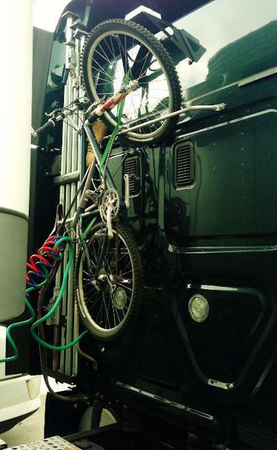 Securely strapped as well as locked, Mario Almendarez’s mountain bike on the back of his tractor’s cab.