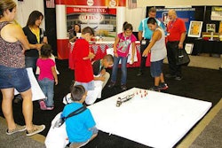 Kids try to back a remote controlled truck at the JBS booth at the Great American Trucking Show in Dallas