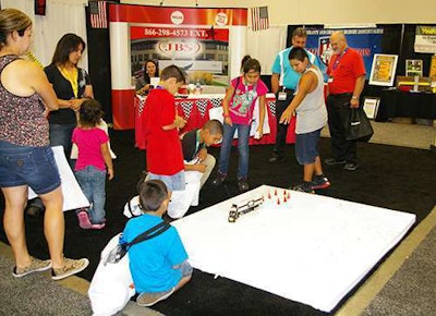 Kids try to back a remote controlled truck at the JBS booth at the Great American Trucking Show in Dallas