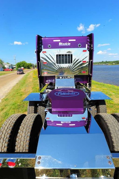 Driver Brent Pecarski keeps the Pete 388’s Violet Effect paint job looking bright, washing and polishing and painting the frame rail that was nicked by gravel.