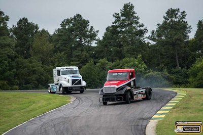 The No. 11 Optima Batteries Freightliner taking a slide in a turn, followed by the No. 23 Bendix Volvo, driven by Hungarian racer Krisztian Szabo.