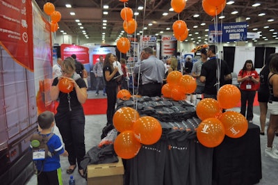 Desarae Veit inflates a balloon for her young visitor at the Transfix booth. The Transfix app enables locating motels and other services on the road, and also is used for load matching.