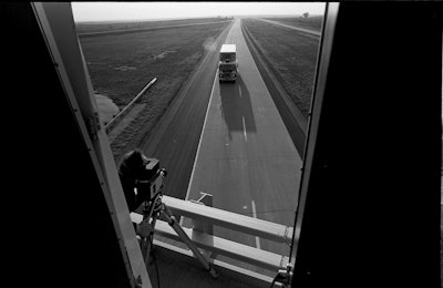 The motor home’s mirror shows Optic Nerve’s Mya Shone, shooting a truck. © Lynn Adler