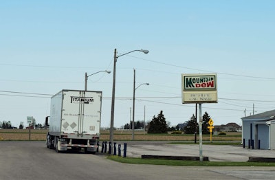 Semi-truck with Titanium trailer parked near an old Mountain Dew car wash sign