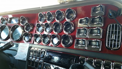 The dash of the rig is dotted with chrome gauges, and it is painted to match the exterior of the truck.