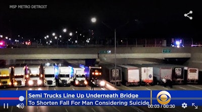 This image, a screen grab from CBS local coverage of the incident, shows 13 truckers assisting in the wee hours early Tuesday, April 25, the Michigan State Police effort to cushion a bridge jumper’s potential fall onto I-696 near Coolidge, Mich.