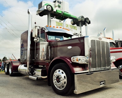 The Federal Motor Carrier Safety Administration held its latest hours of service listening session in conjunction with Guilty by Association Truck Show in Joplin, Mo., at 4 State Trucks headquarters, long popular with owner-ops and small fleets. Pictured: Illinois-based small fleet owner-op Dave Marti’s relatively recent addition to the fleet (a 2018 Peterbilt 389 Cat-powered glider) under the iconic “Mobsled” high in the air outside 4 State.