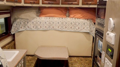 The interior of the 120-inch custom sleeper includes a fold-down full-size bed, a table, kitchen amenities, bathroom and more.