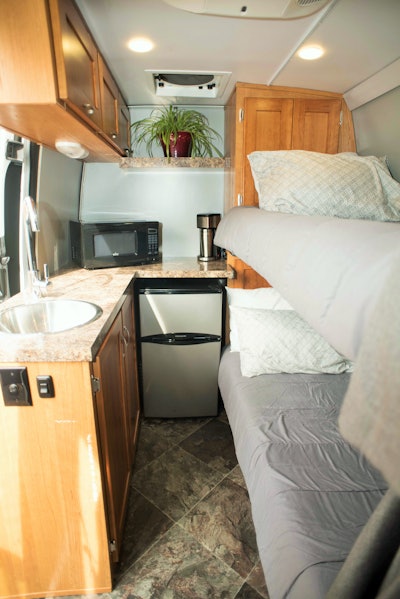 SLEEPER IN A CARGO VAN? | While it’s common for cargo van expediters to run with a small cot that, folded up, can be stowed against a wall of the hold when space is needed for freight, various conversion companies exist for more permanent sleeper treatments. One example is this 8-foot area viewed from behind the front seats in Darren and Trish Ayres’ Mercedes Sprinter. The two designed it with Fastlane Products of Oak Ridge, Tennessee. Tax, tag, title and the upfit added a little less than $20,000 to the roughly $45,000 price of the basic van with super singles and extended length. Follow this link to hear more from Darren on the business and the sleeper conversion in particular.