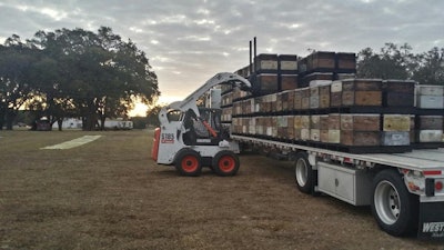 Bud and Aneisha Chapel don bee suits when they load hives onto their trailer. The husband-and-wife team drives a 2018 Kenworth T680.