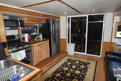 The living area includes most of the appliances found in a home kitchen. Behind the sliding door is storage for vehicles, including a car lift.