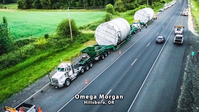 When Omega Morgan was hired to move these tanks, several routing and safety challenges faced the convoy, which consisted of more than 20 vehicles all told, arrayed in a convoy with two pilot cars ahead of and behind, and separating, the two haul vehicles, also including an array of bucket trucks from numerous utilities along the way. The company found a route that could accommodate two simultaneous loads and engineered a crane load of the tanks onto the deck trailers. When local power companies wanted to avoid subcontracting the work of lifting and removing all of the associated electrical wires, Omega sourced, directed and coordinated the efforts of a number of different utility companies for the duration of the haul. In all, Omega put in more than 1,000 man-hours and navigated a large and intricate haul across mostly two-lane roads with no incidents — and on-budget.
