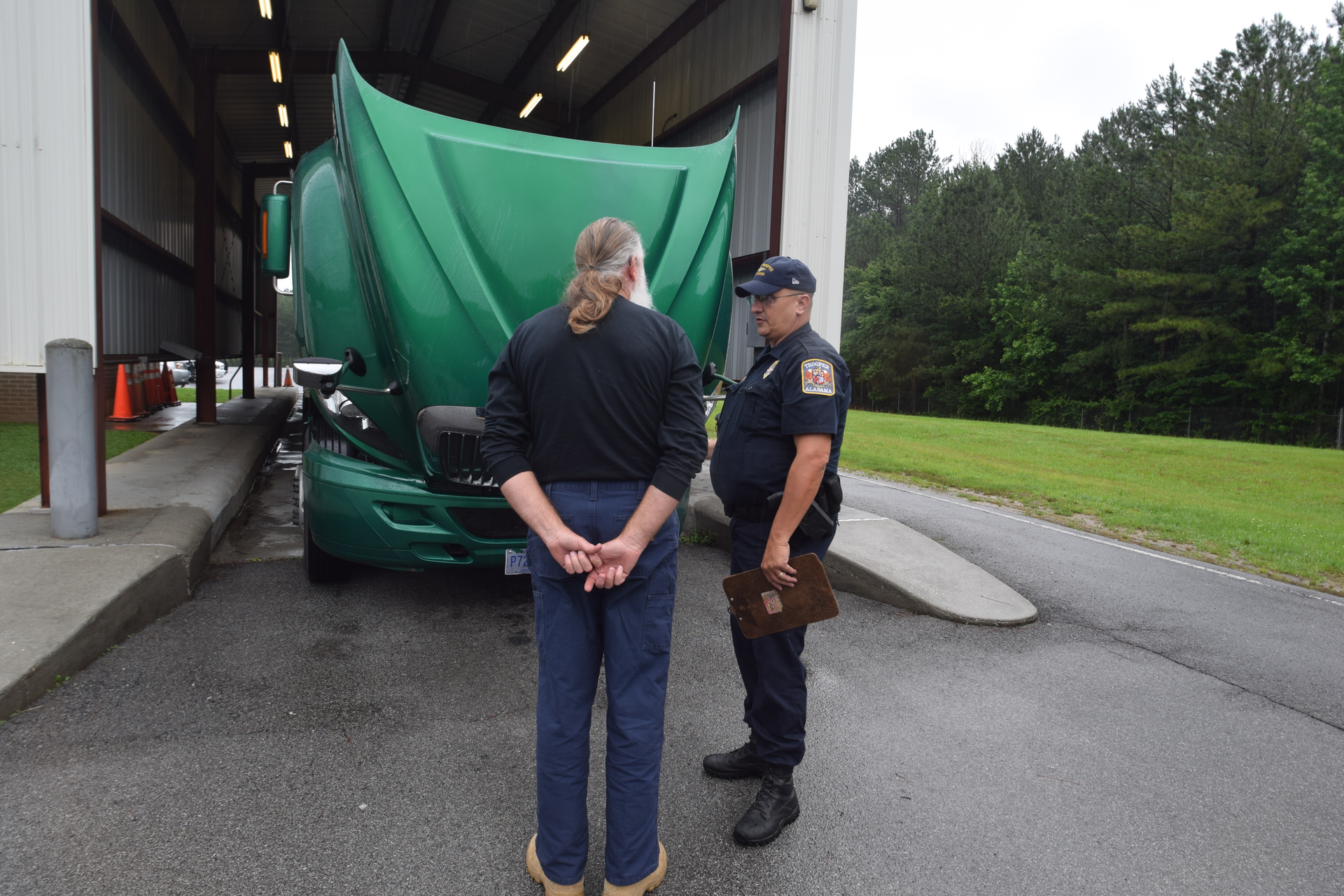 Truck driver and enforcement officer talking in front of truck being inspected