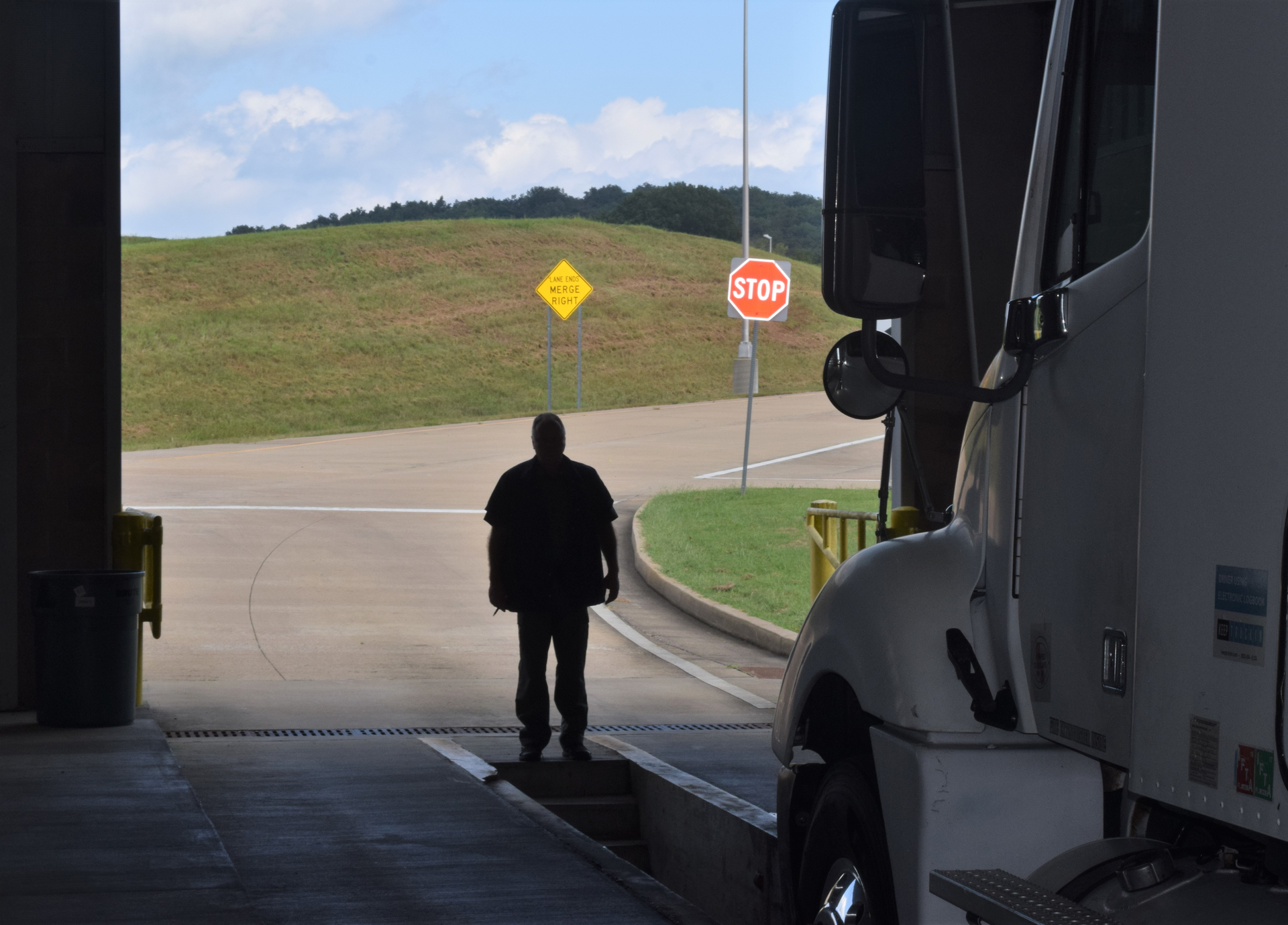 Man standing in open service area in front of semi truck