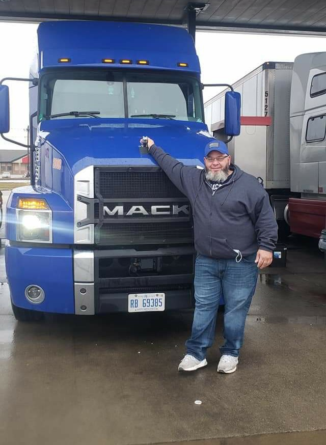 Anthony Townley Sr. standing in front of a blue Mack semi-truck