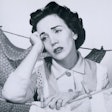 a woman resting her elbow on a clothesline with a sad face