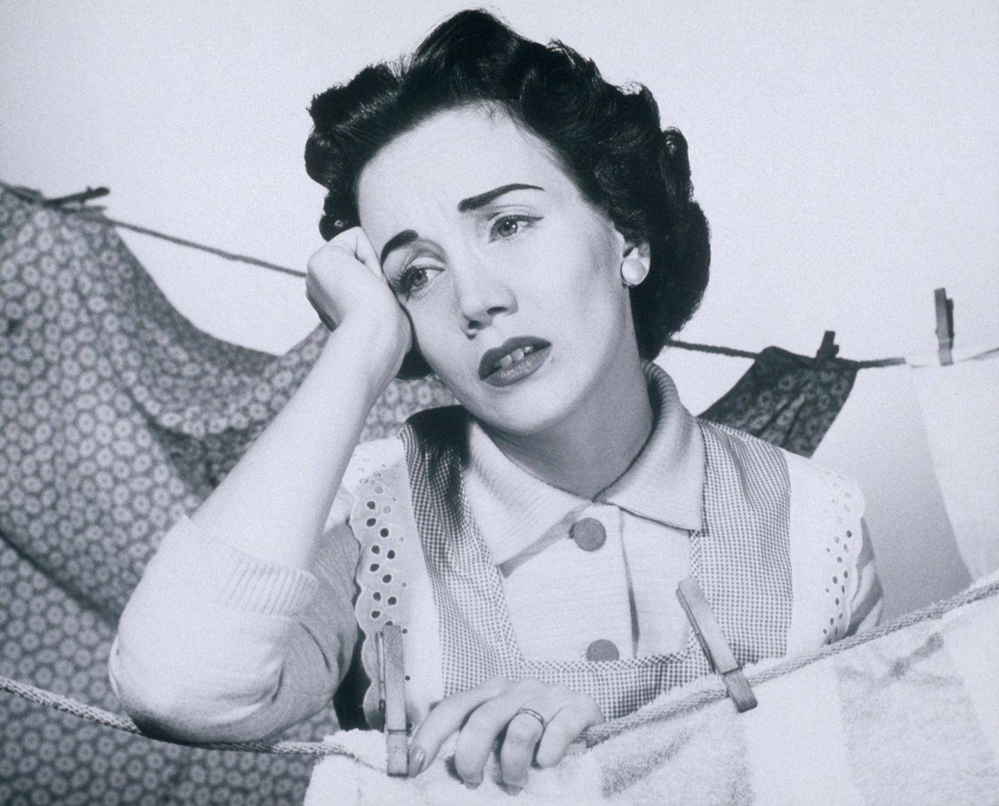 a woman resting her elbow on a clothesline with a sad face