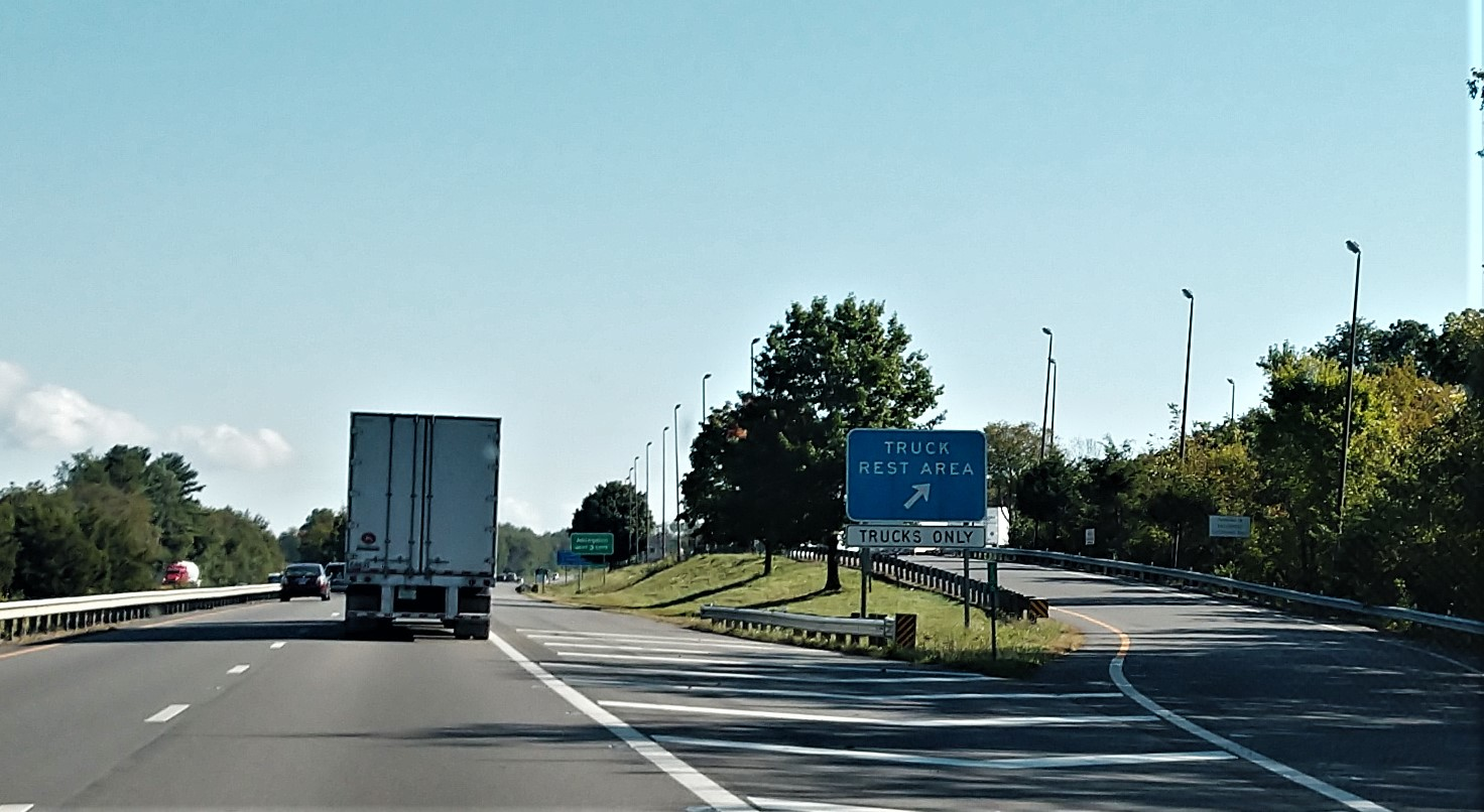 Cars and trucks driving on highway passing by truck rest area exit