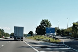 Cars and trucks driving on highway passing by truck rest area exit