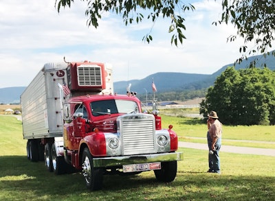 man standing outside of semi truck in field