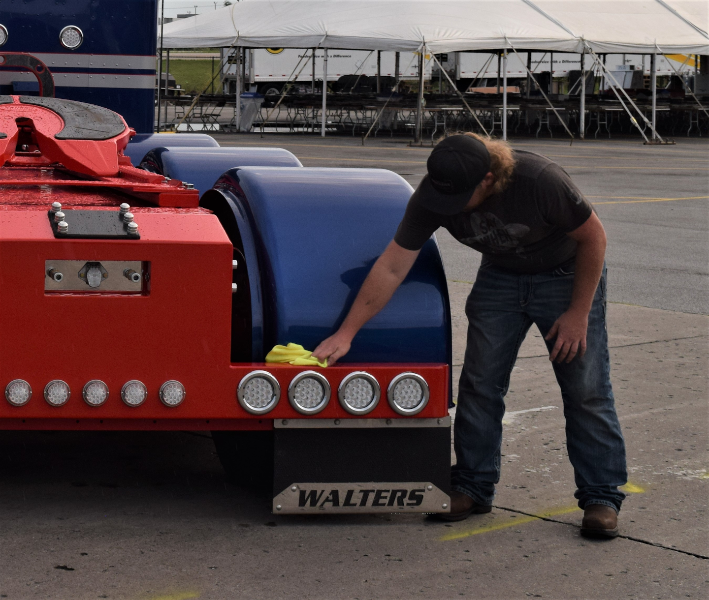 Pipestone, Minnesota-based owner-operator Aaron Walters wipes raindrops from the bumper of his 2019 four-axle Peterbilt 389, showing the next two days at the Walcott Truckers Jamboree at the Iowa 80 Truck Stop.