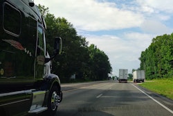 two semi-trucks on a highway passing a semi-truck pulled over on the side