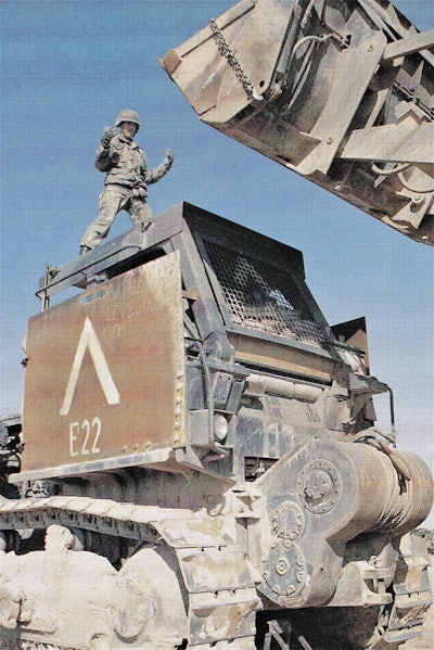During the Gulf War, W. Joel Baker directs a bulldozer while loading a trailer