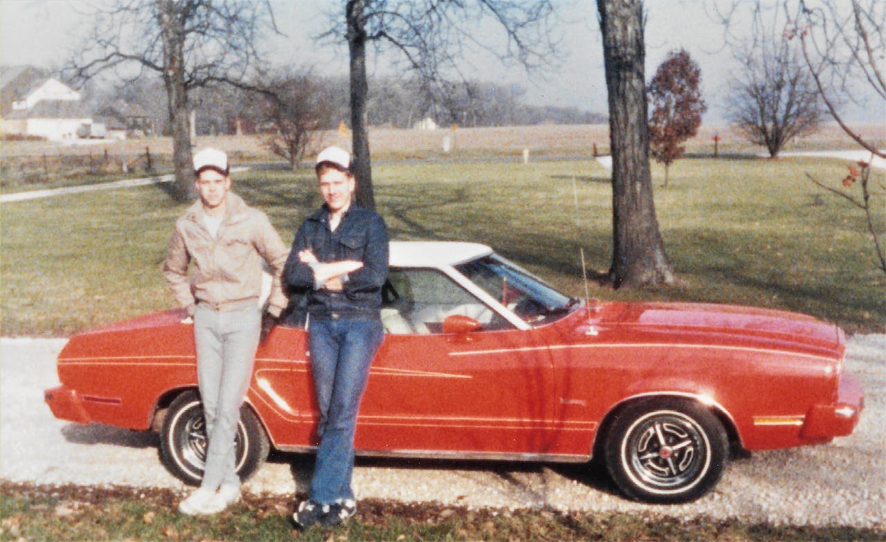 W. Joel Baker pictured with a friend by an old Ford Mustang on break from military training in the 1980s