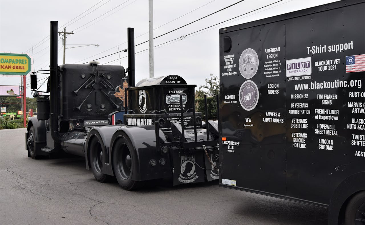 The Freightliner is powered by a Detroit Series 60 running at 650 horsepower, with a 15-speed double over transmission and a heavy-duty bumper hitch that pulls a 2019 USA Trailer 16-foot box, carrying flagpoles and flags unfurled in specially designed mounts on the tractor's deck during tribute events – and much more besides.
