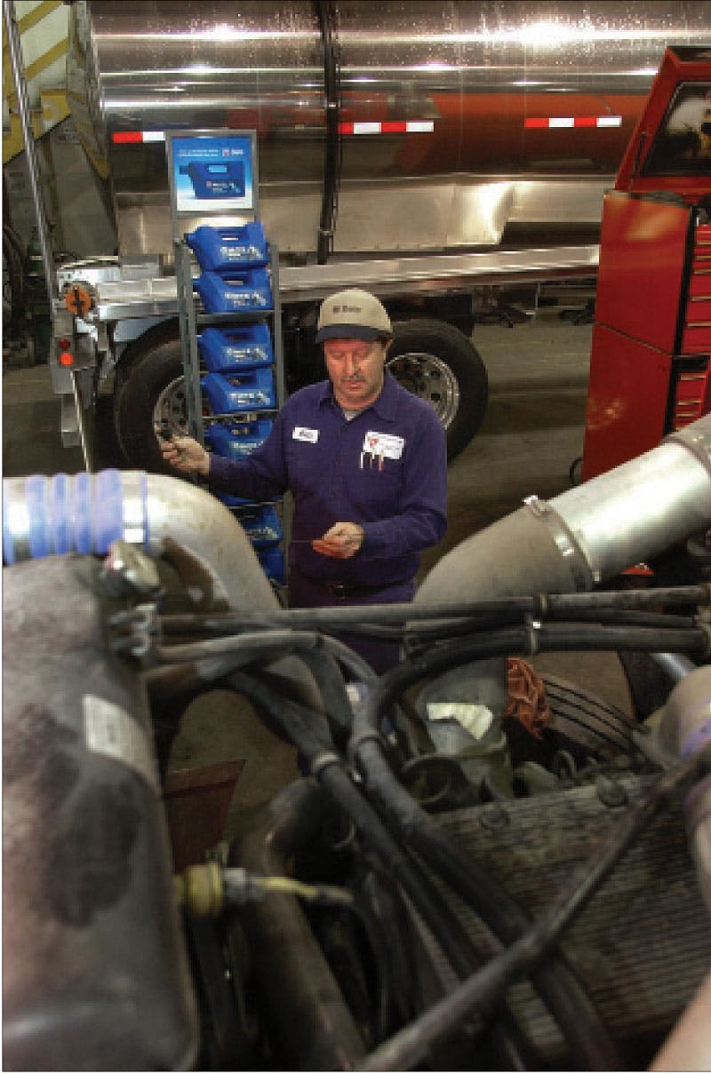 diesel tech checks oil dipstick level