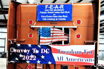 Banners featured on the back of owner-operator Ruben Carrion's well-known custom 2000 Peterbilt 379. The picture was taken at Ted Everett Farm Equipment, where the People's Convoy gathered for a day off from movement on Wednesday.