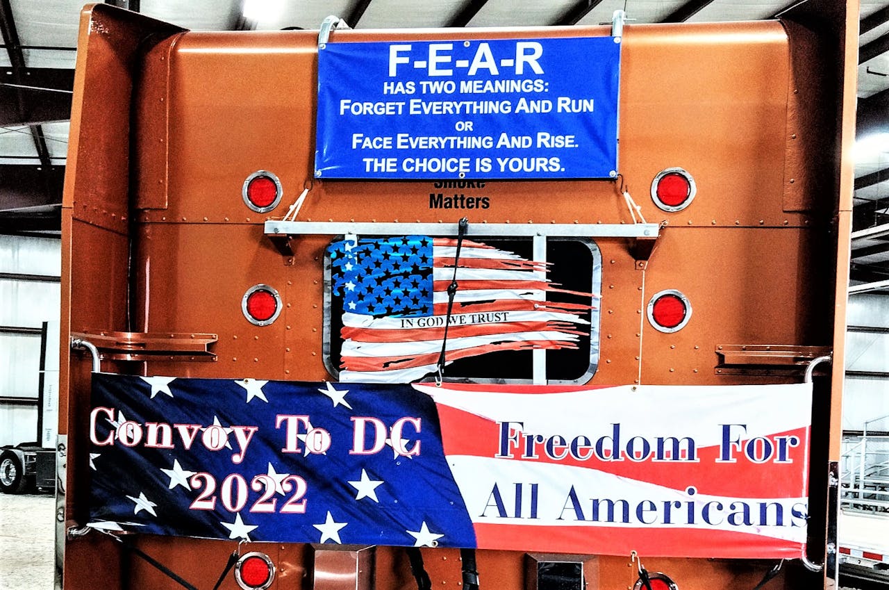 Banners featured on the back of owner-operator Ruben Carrion's well-known custom 2000 Peterbilt 379. The picture was taken at Ted Everett Farm Equipment, where the People's Convoy gathered for a day off from movement on Wednesday.