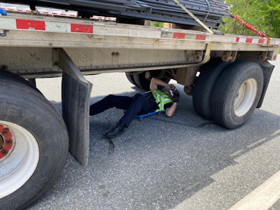 A DMV officer checks the brakes on a trailer.
