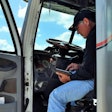 Owner-operator in driver's seat look at load board on tablet