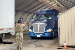 an airman waving a truck forward on a military base.