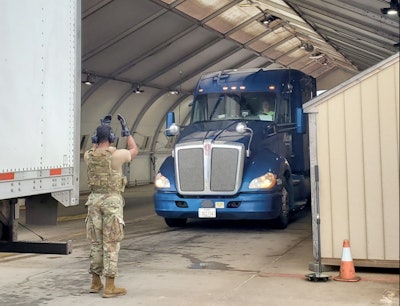 an airman waving a truck forward on a military base.