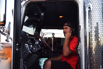 owner-operator talking on cell phone in truck's driver seat