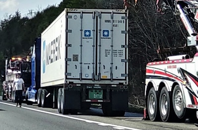 semi-truck and tow truck on side of road