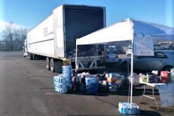 Semi-truck with opened trailer behind a tent with a posted kentucky tornado relief sign