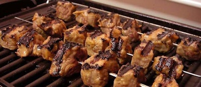 meat on skewers on a grill grate
