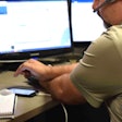 broker at desk looking at phone/computer terminal