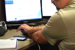 broker at desk looking at phone/computer terminal