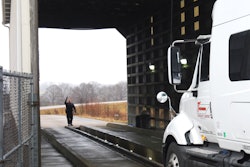 Semi-truck entering an inspection barn with an officer at the opposite end directing the driver