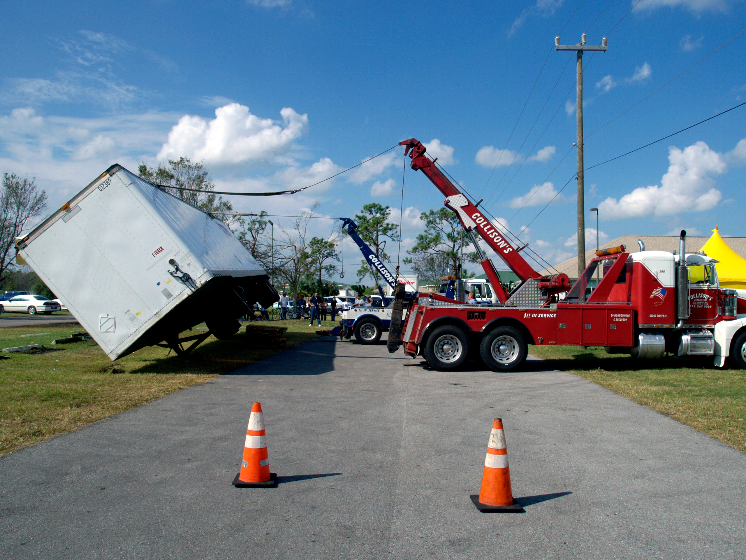 Red tow truck lifting a turned over semi-truck trailer
